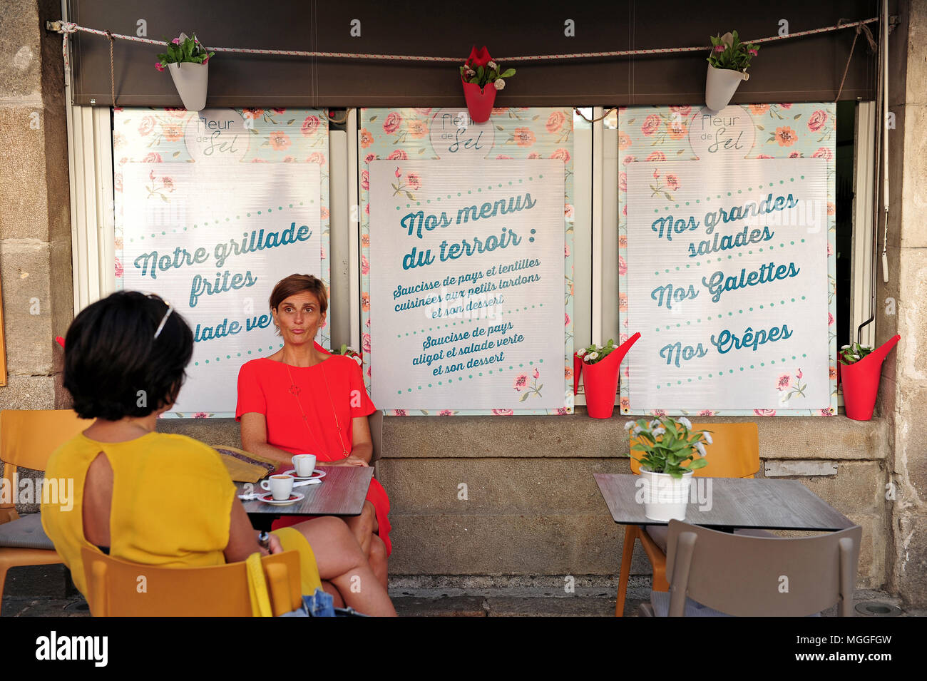 Two women drinking coffee in a restaurant advertising local products in Le-Puy-en-Velay, France Stock Photo
