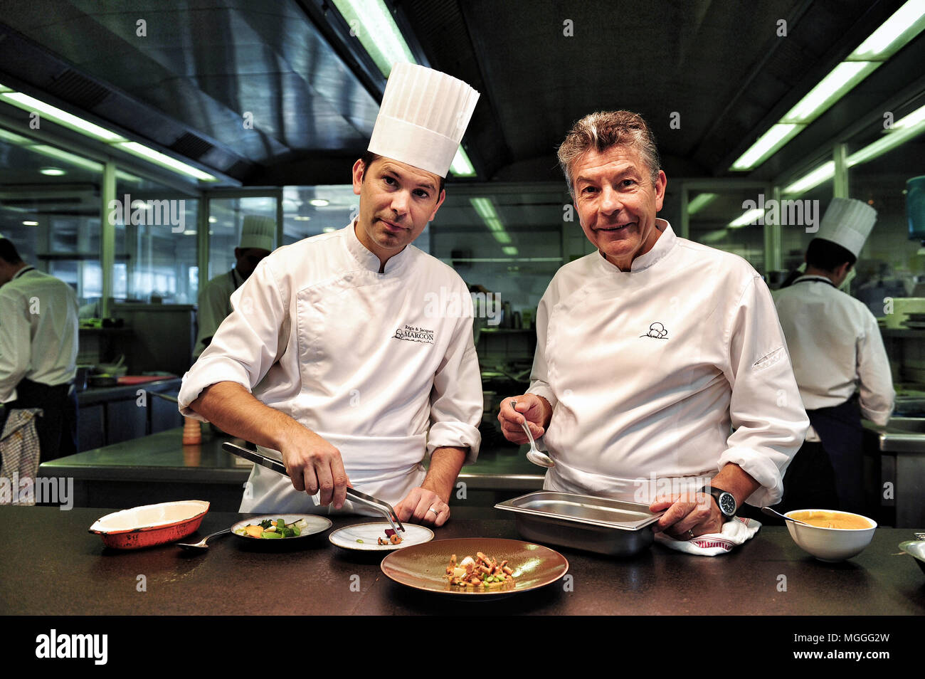 Three-starred chef Régis Marcon (right) at work with his son Jacques (left) in the kitchen of his restaurant in Saint-Bonnet-le-Froid, France Stock Photo