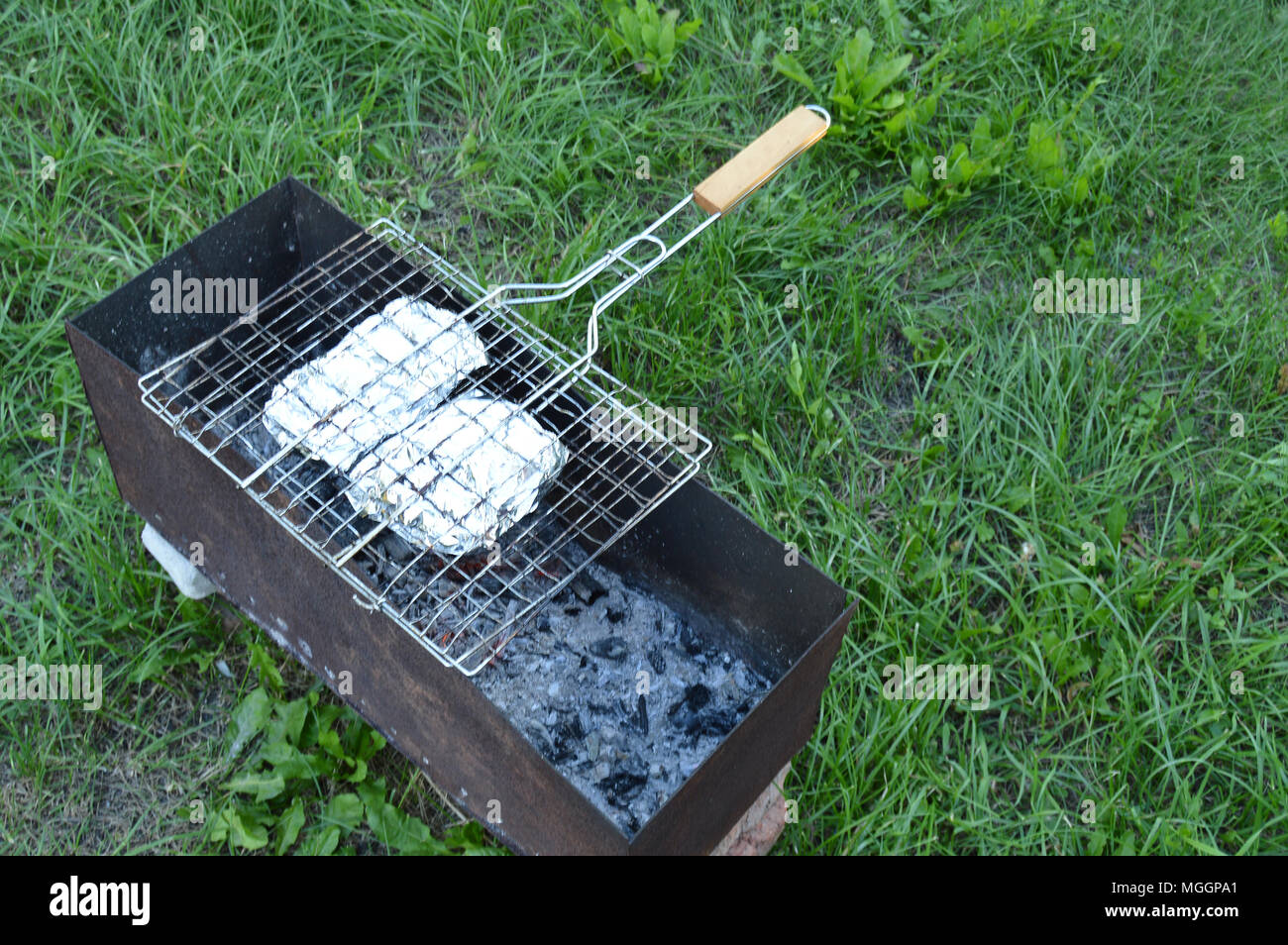 Grill with meat and vegetables in foil is on the grill. Cooking on a