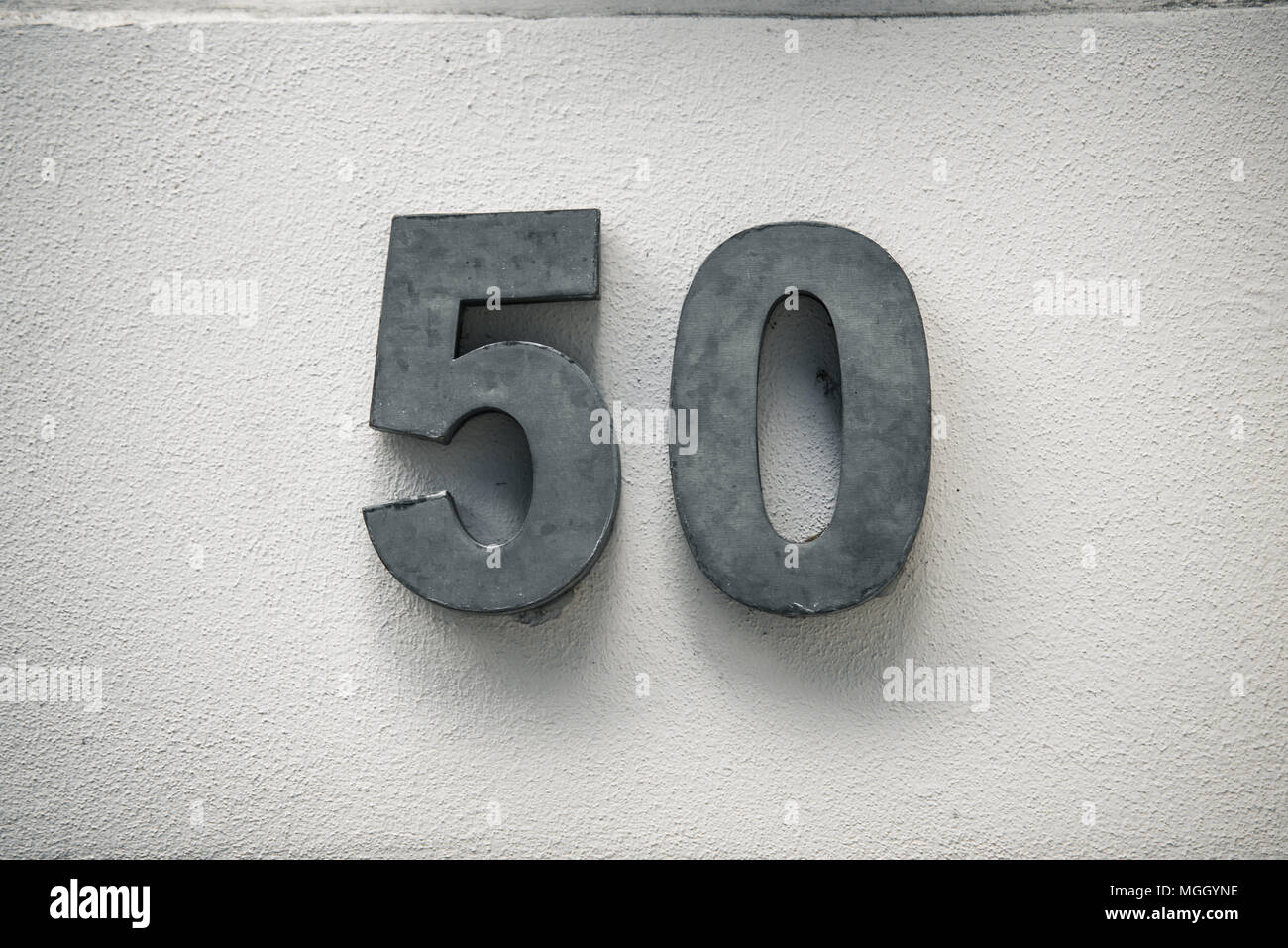 fifty 50 number on white wall metal numbers Stock Photo