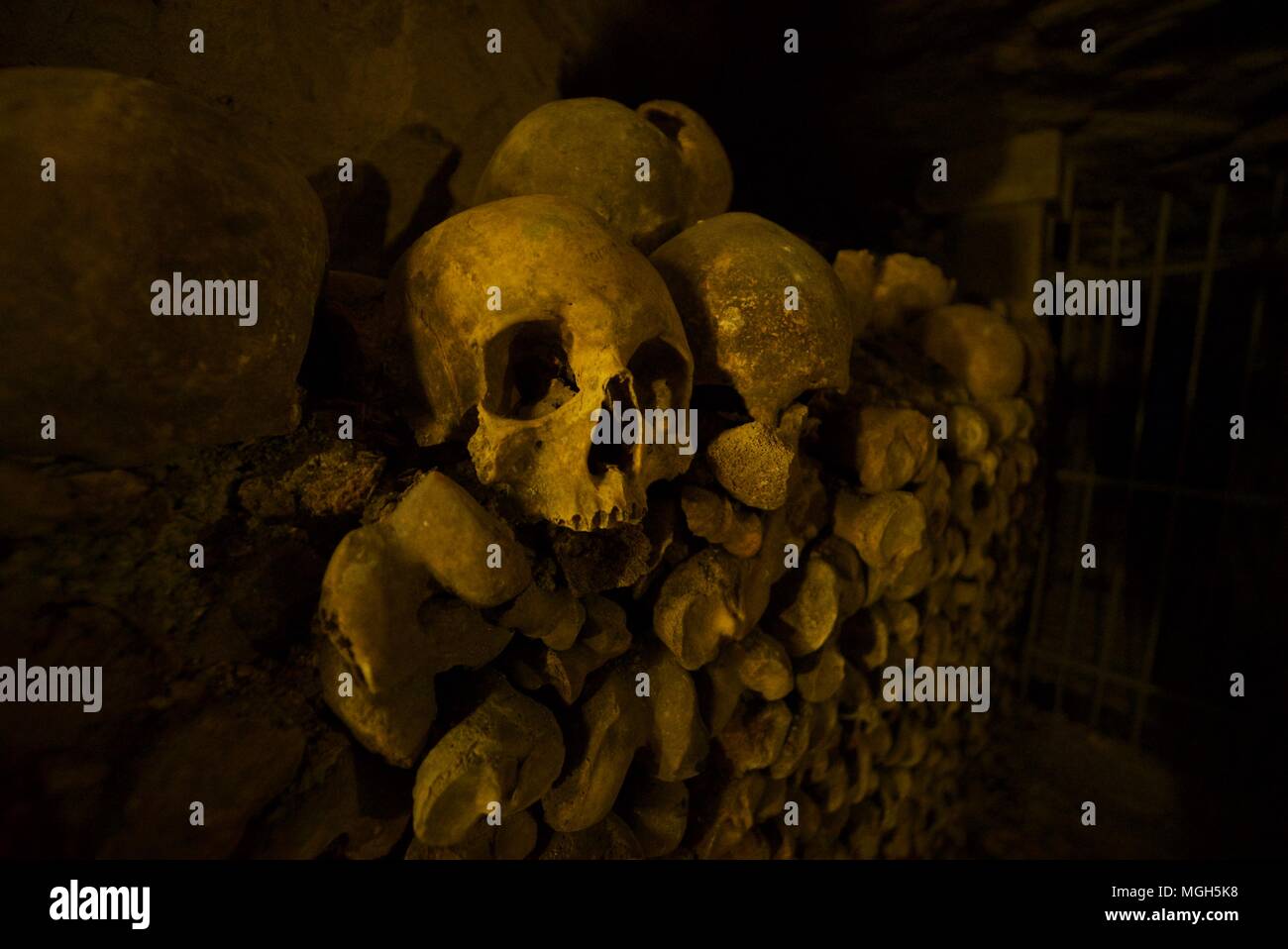 Human skull on top of pile of bones inside the Paris catacombs Stock Photo