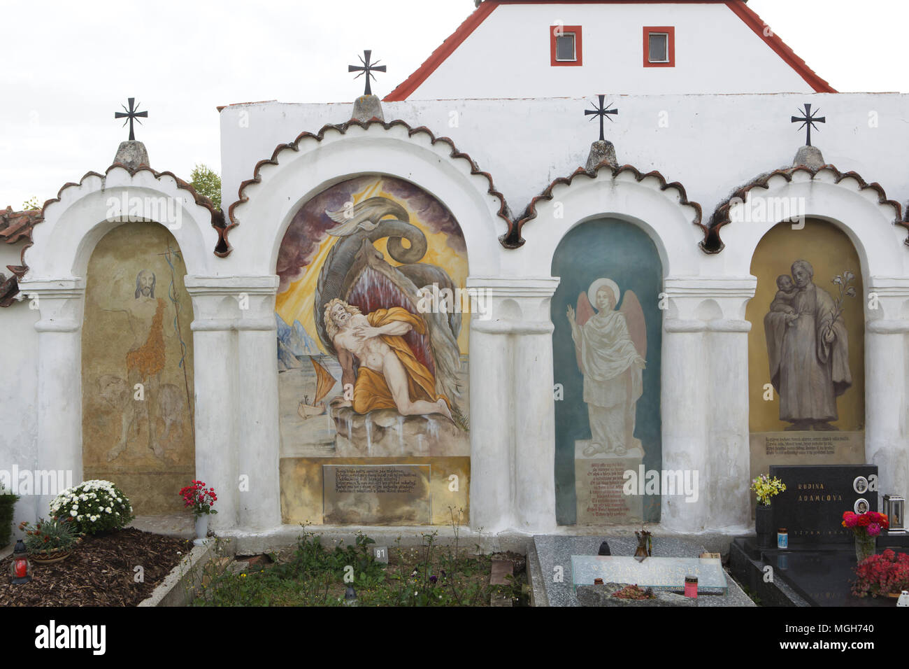 Funeral chapels with mural paintings at the village cemetery in Albrechtice nad Vltavou in South Bohemian Region, Czech Republic. Saint John the Baptist, Jonah and the Giant Fish and the Angel are depicted in the chapels from left to right. Funeral chapels placed on the cemetery wall were decorated with murals in the 1840s by local painter František Mikule conducted with parish priest Vít Cíza, who also composed poems for each mural. The murals were repainted several times during the 19th and 20th centuries and completely restored by the team led by Jitka Musilová in 2010-2013. Stock Photo