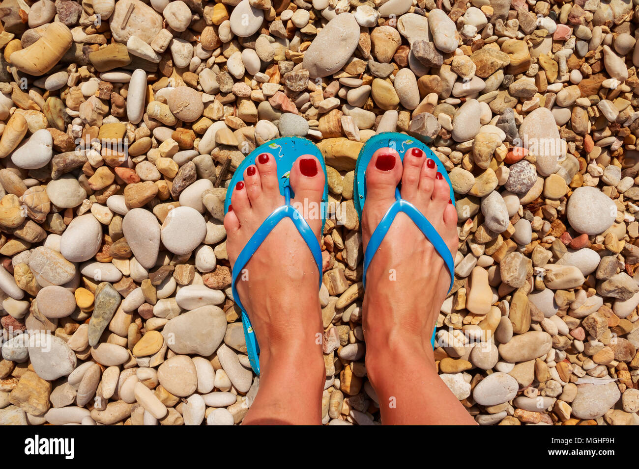 Low section of woman wearing slippers while standing on board walk.First  person perspective, view on own feet. Rocky beach.Female legs wearing flip  flops near sea. top view Stock Photo - Alamy