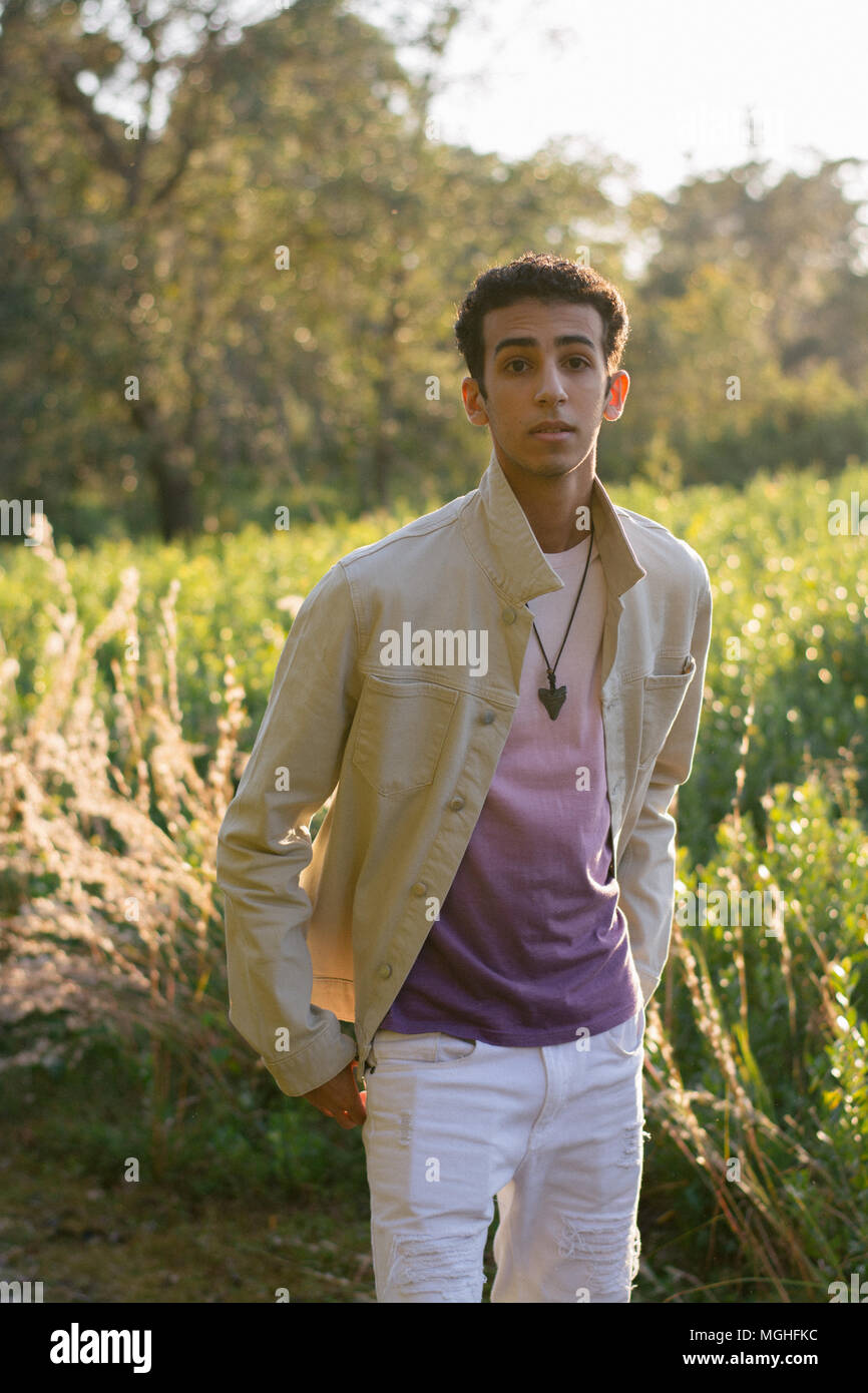 Young caucasian male model posing while sitting on the floor in the studio.  Teenage boy in stylish clothes on a pink background Stock Photo - Alamy