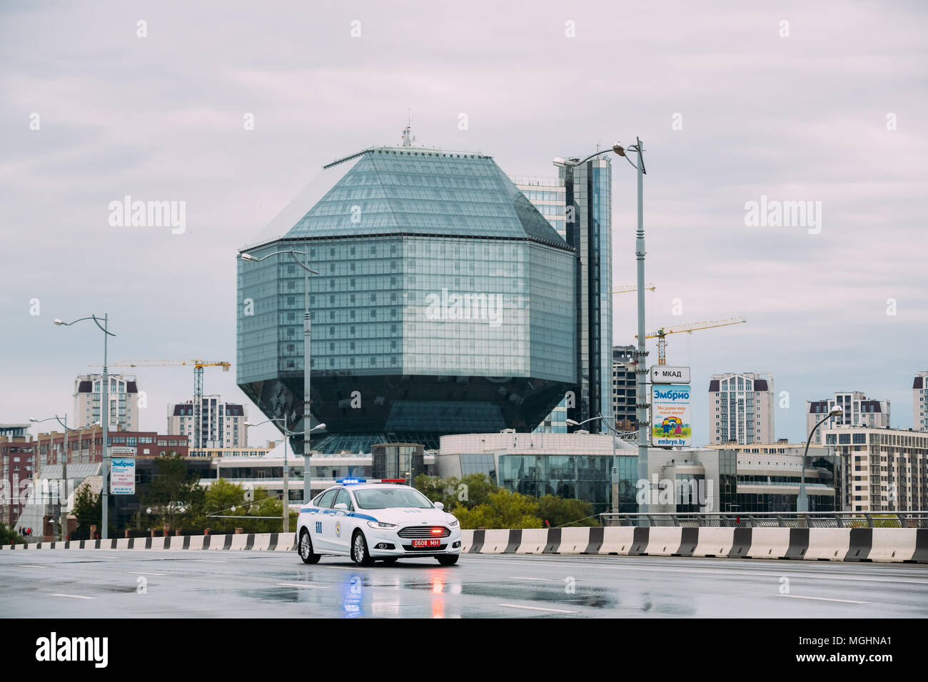 Minsk, Belarus. Police Car Moving In Town Street Near National Library At Rainy Summer Day. Stock Photo