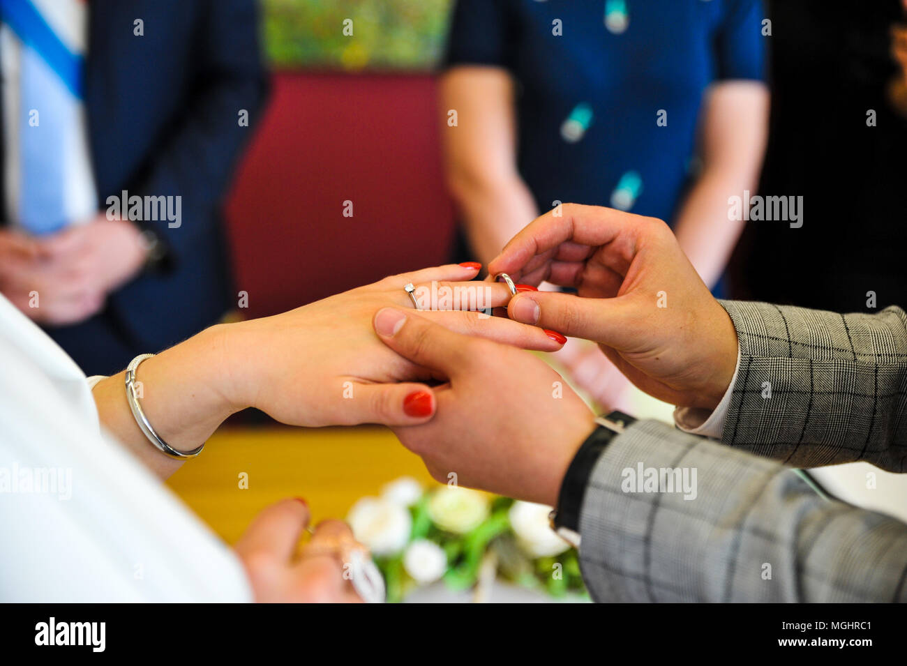 Groom wearing a ring on bride's finger during wedding ceremony Stock Photo
