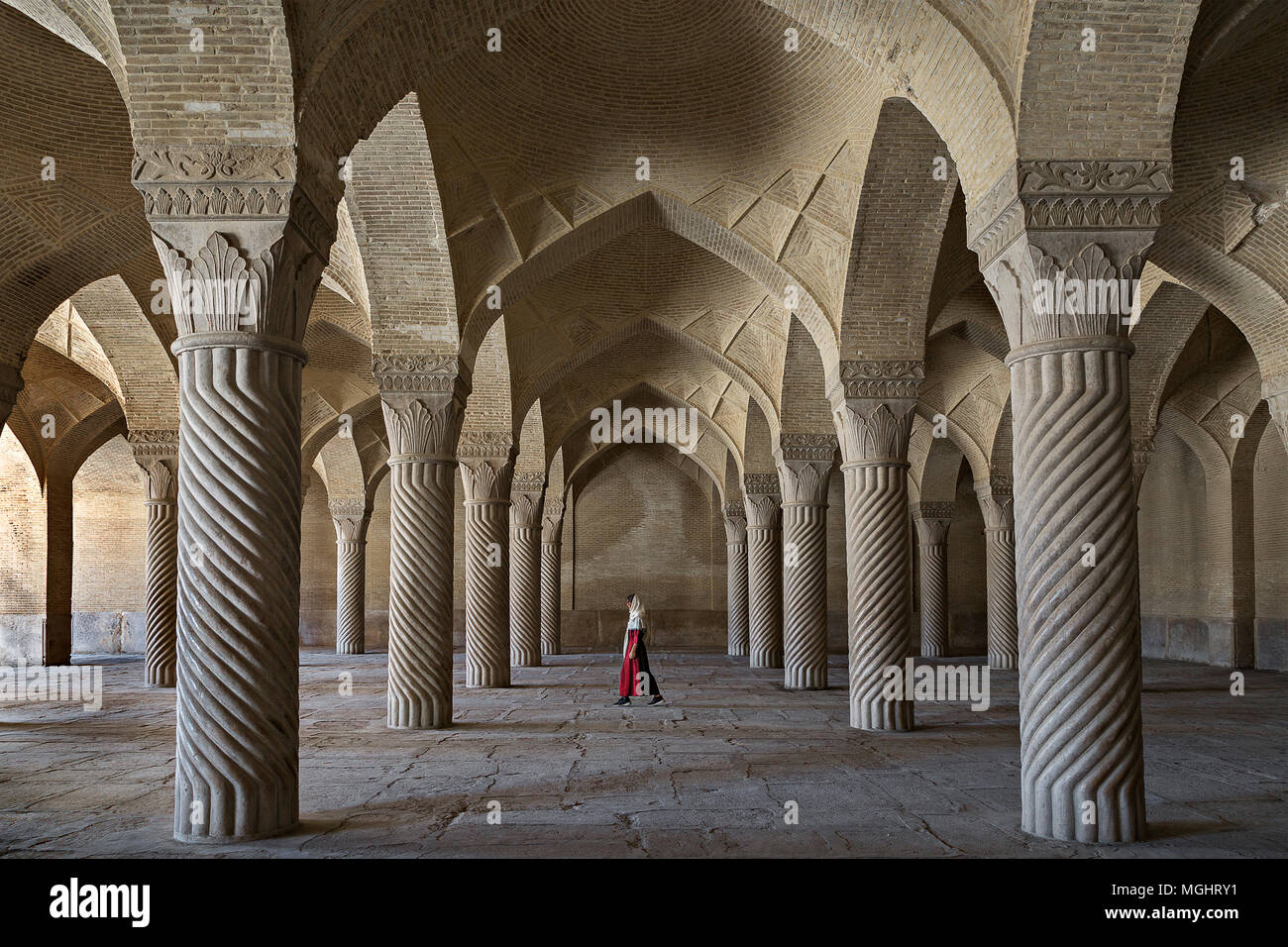 Vakil Mosque with an Iranian woman in red dress under its arches, in Shiraz, Iran Stock Photo