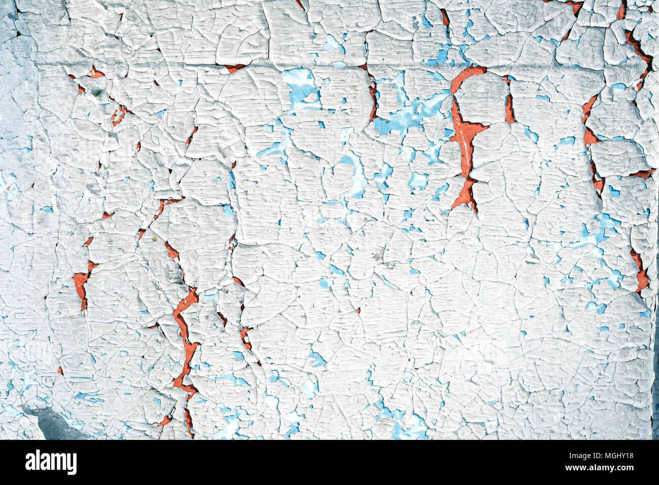 Old flaking blue paint with an orange vibrant undercoat showing up through cracked broken plaster with a copyspace area for DIY reconstruction and bui Stock Photo