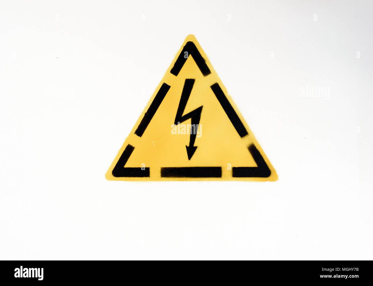 Yellow and black spray painted electricity warning sign created from a template on a white painted background Stock Photo