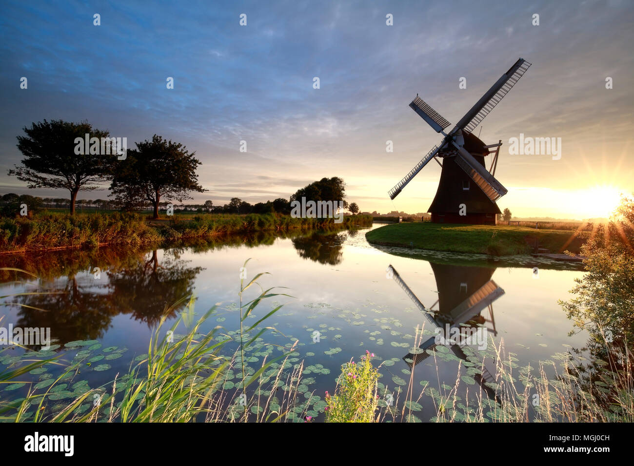 beautiful summer sunrise over windmill by river Stock Photo - Alamy