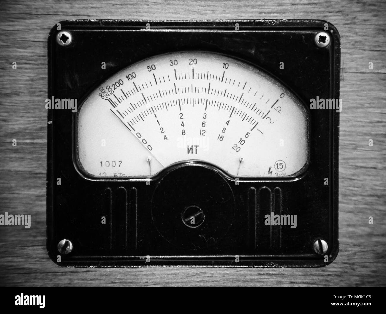Close-up monochrome photo of vintage electric voltmeter in wooden panel Stock Photo