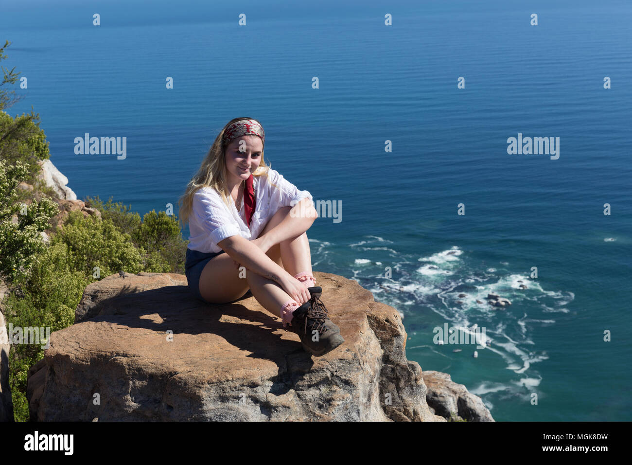 A pretty blonde woman admires the view after hiking up Lion's Head in Cape Town, South Africa Stock Photo