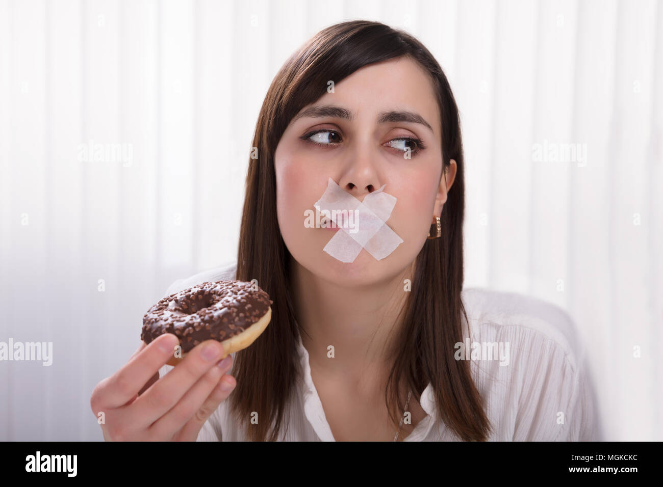 Closeup Of A Young Woman With Sticky Tape Over Her Mouth Unable To Eat