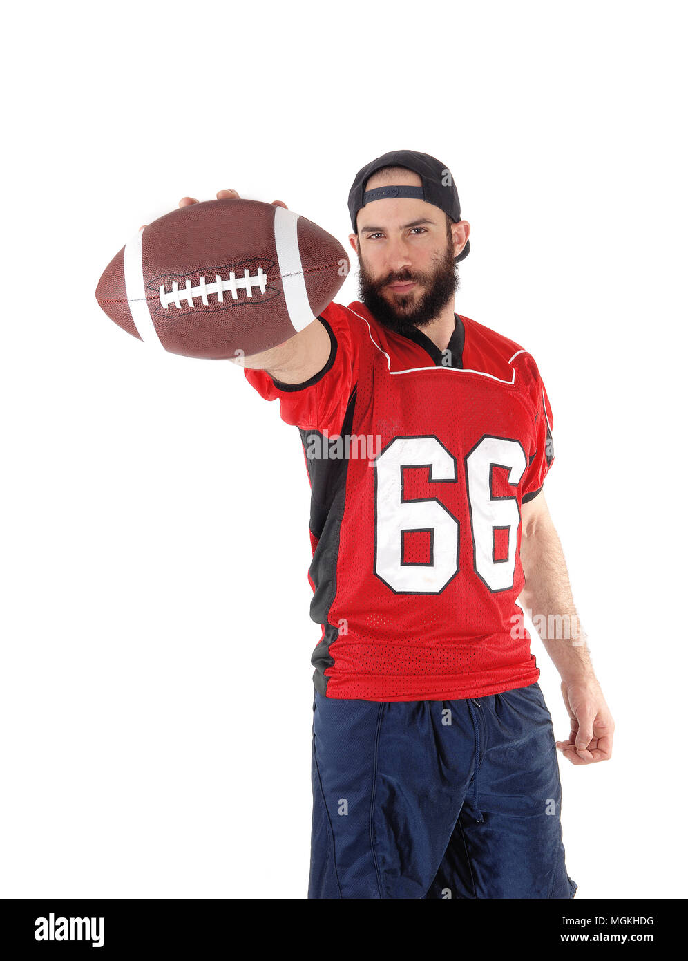 A young football player standing in his uniform and a beard and