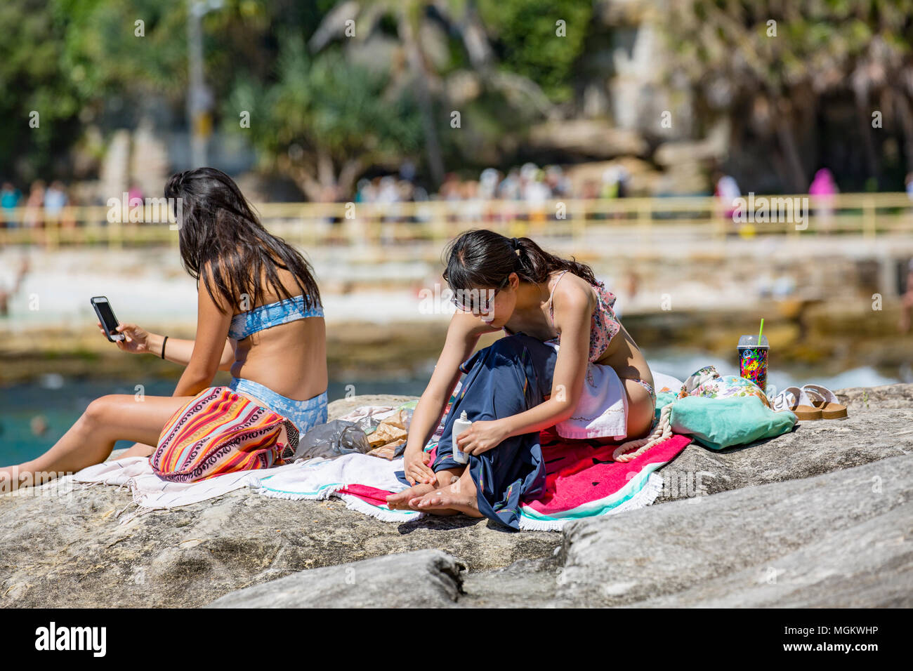 Young black hair asian girls sunbathe on the rocks at Fairy Bower in Manly beach,Sydney,Australia Stock Photo