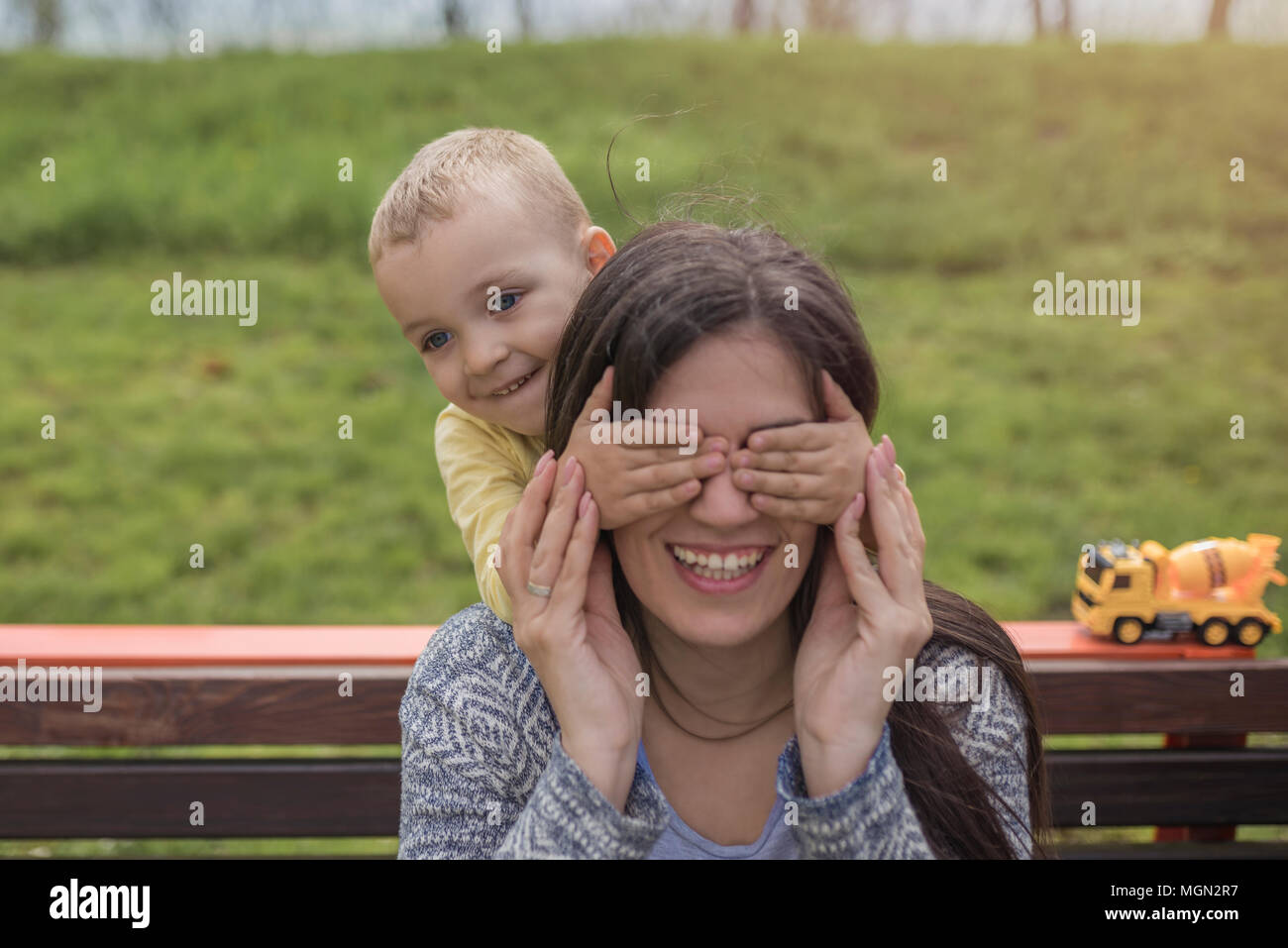 Closeup portrait of a happy mother and son playing on playground and having fun. Young mother playing with her baby outside in park. Mom and son. Stock Photo