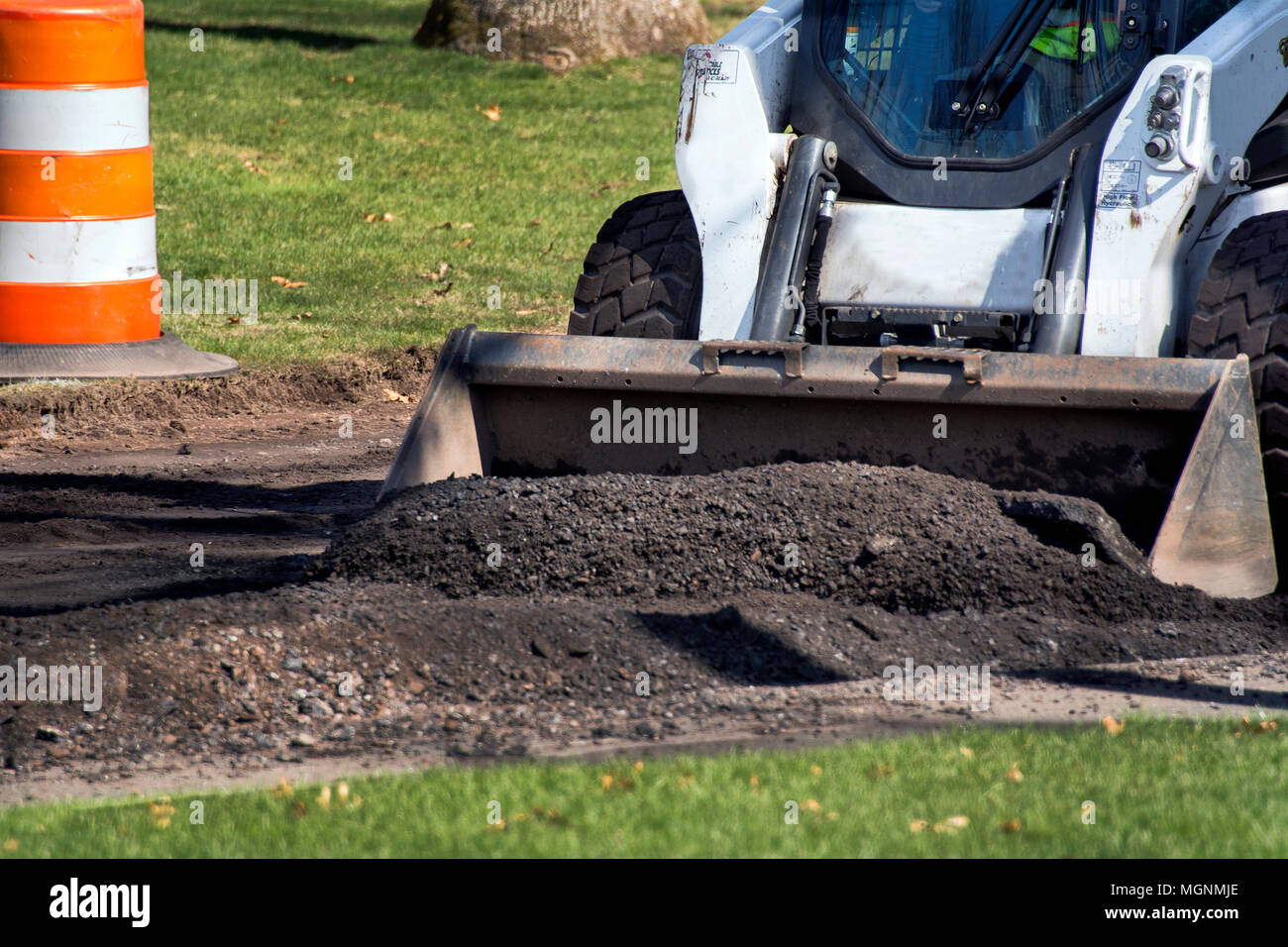 Compact excavator used in road resurfacing work Stock Photo