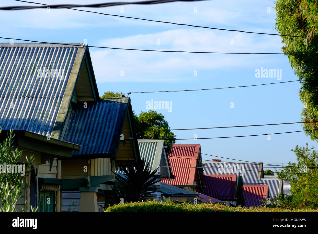 Suburban corrugated iron roof tops and electrical cables tops in profile in Coburg, a suburb of Melbourne, Victoria Stock Photo