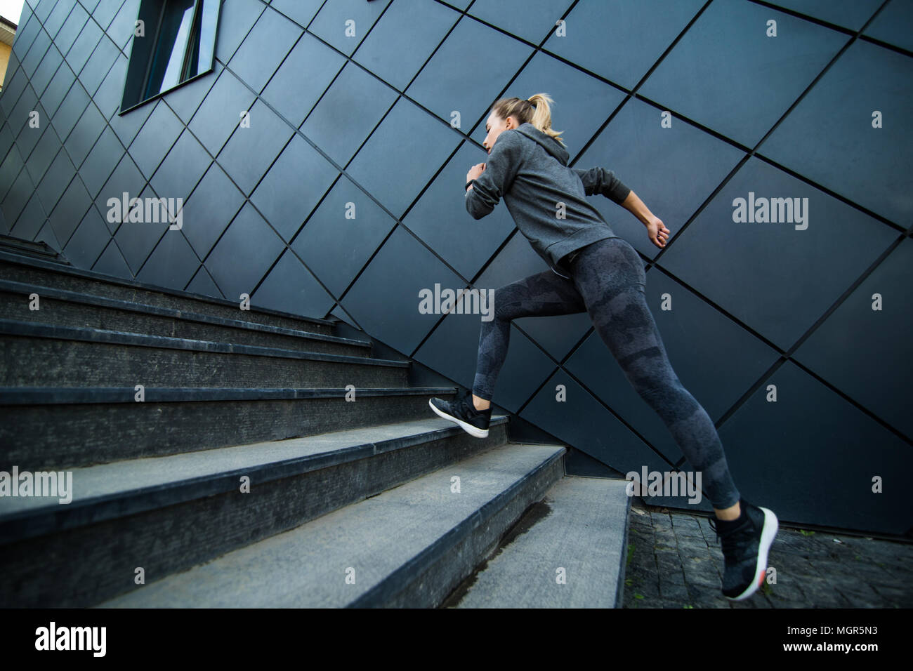 Female athlete running fast up the stairs staircase workout Stock