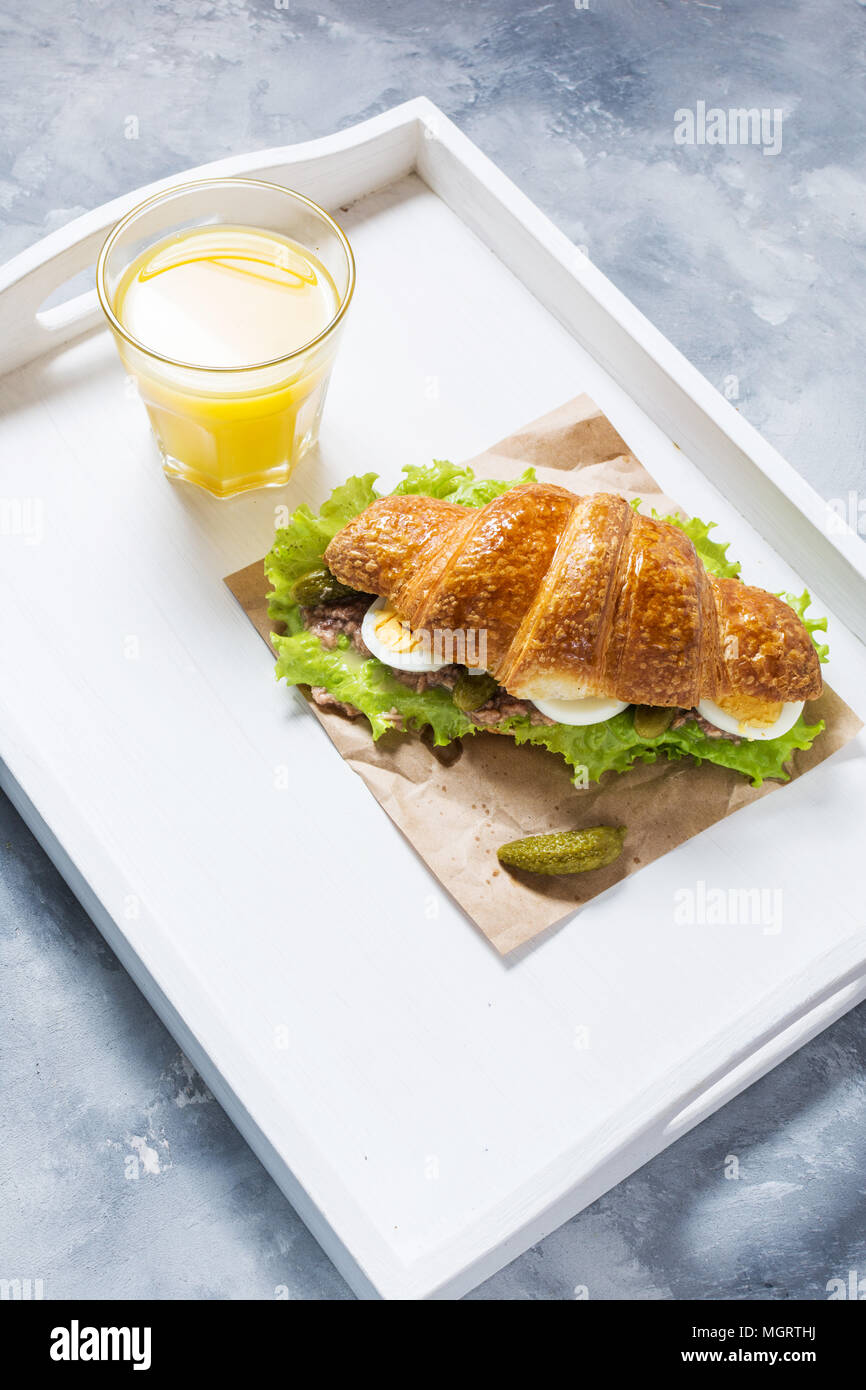 Croissant sandwich with tuna, hard boiled egg, salad and cucumber on