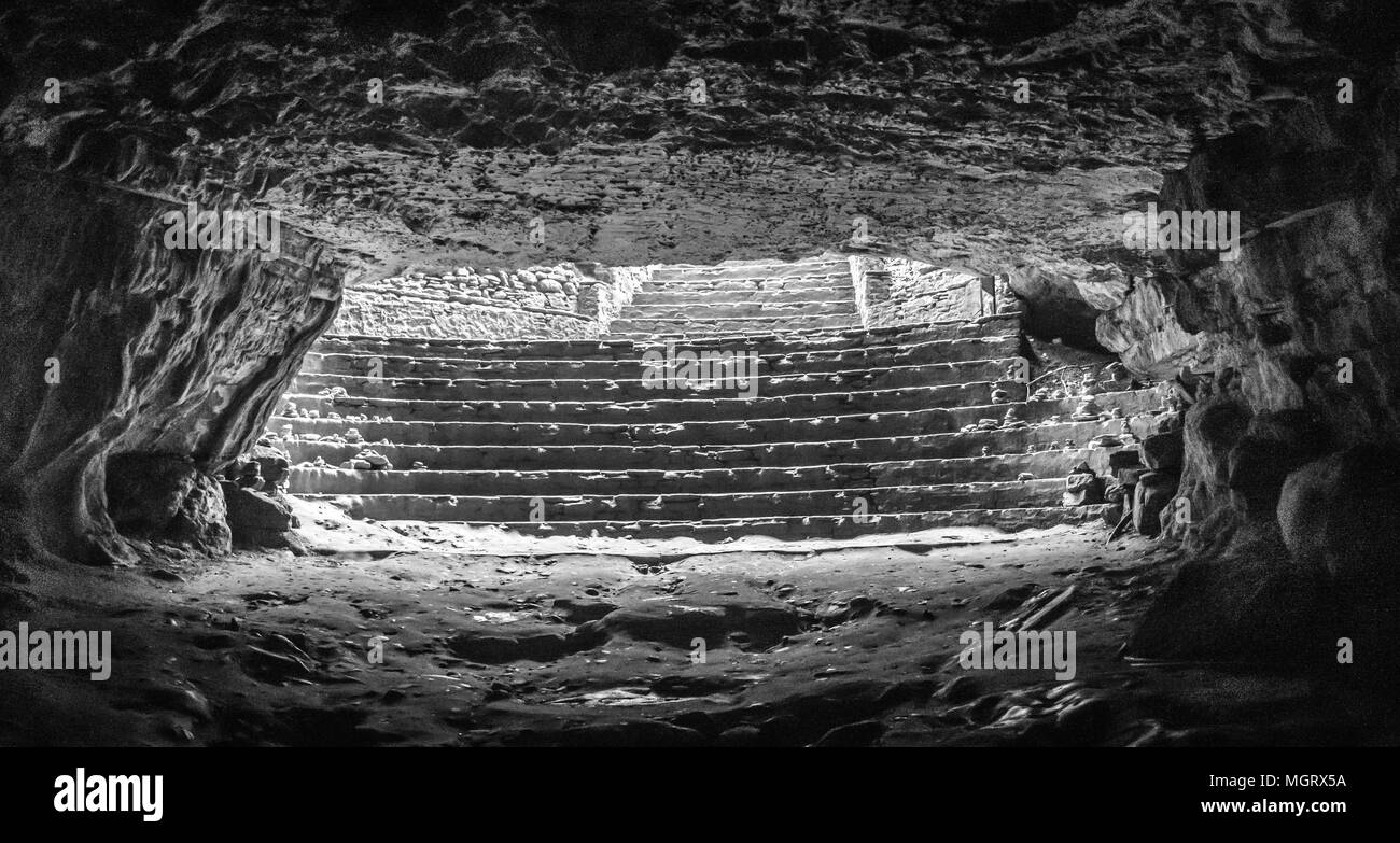 Stairs of a cave entrance, very dark and wet low light muddy very much risky to walk on it. The cave is built of stone. Light cant reach into it. Brig Stock Photo