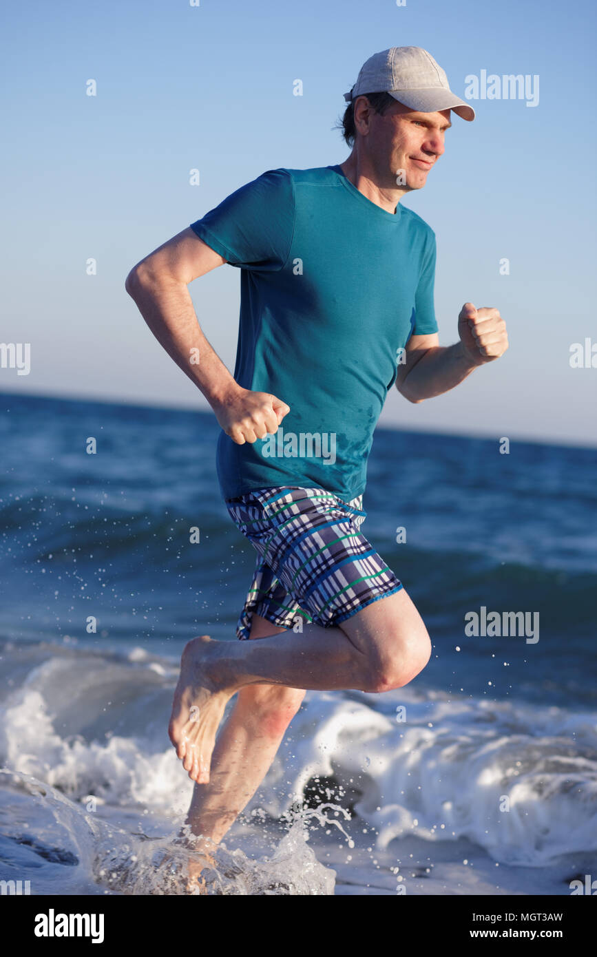 Barefoot mature man during jogging on a beach Stock Photo