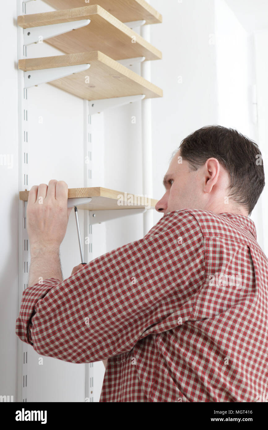 Man installing wooden shelves on brackets Stock Photo