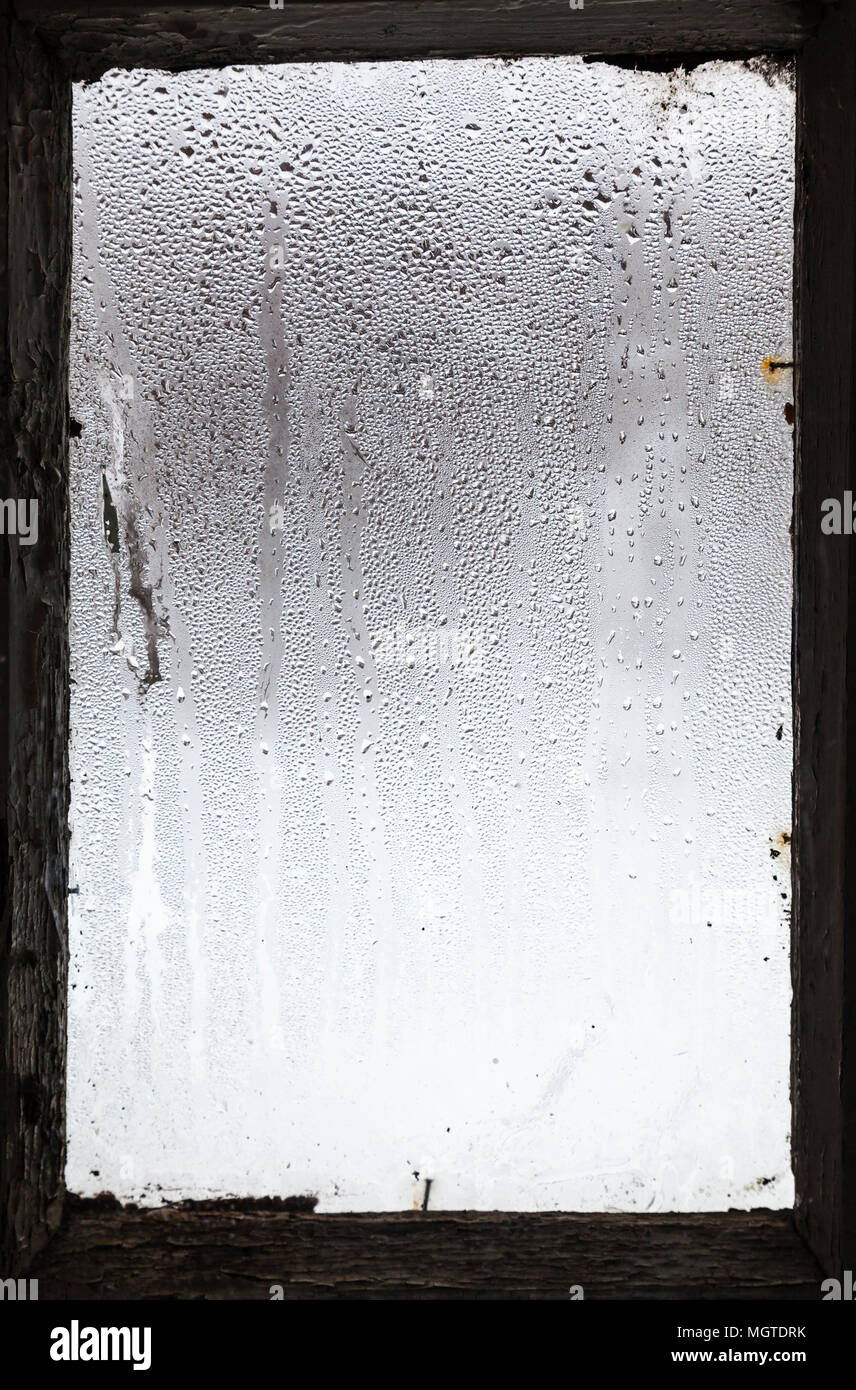 water drops from melting snow on surface of misted window in old rural house in winter Stock Photo