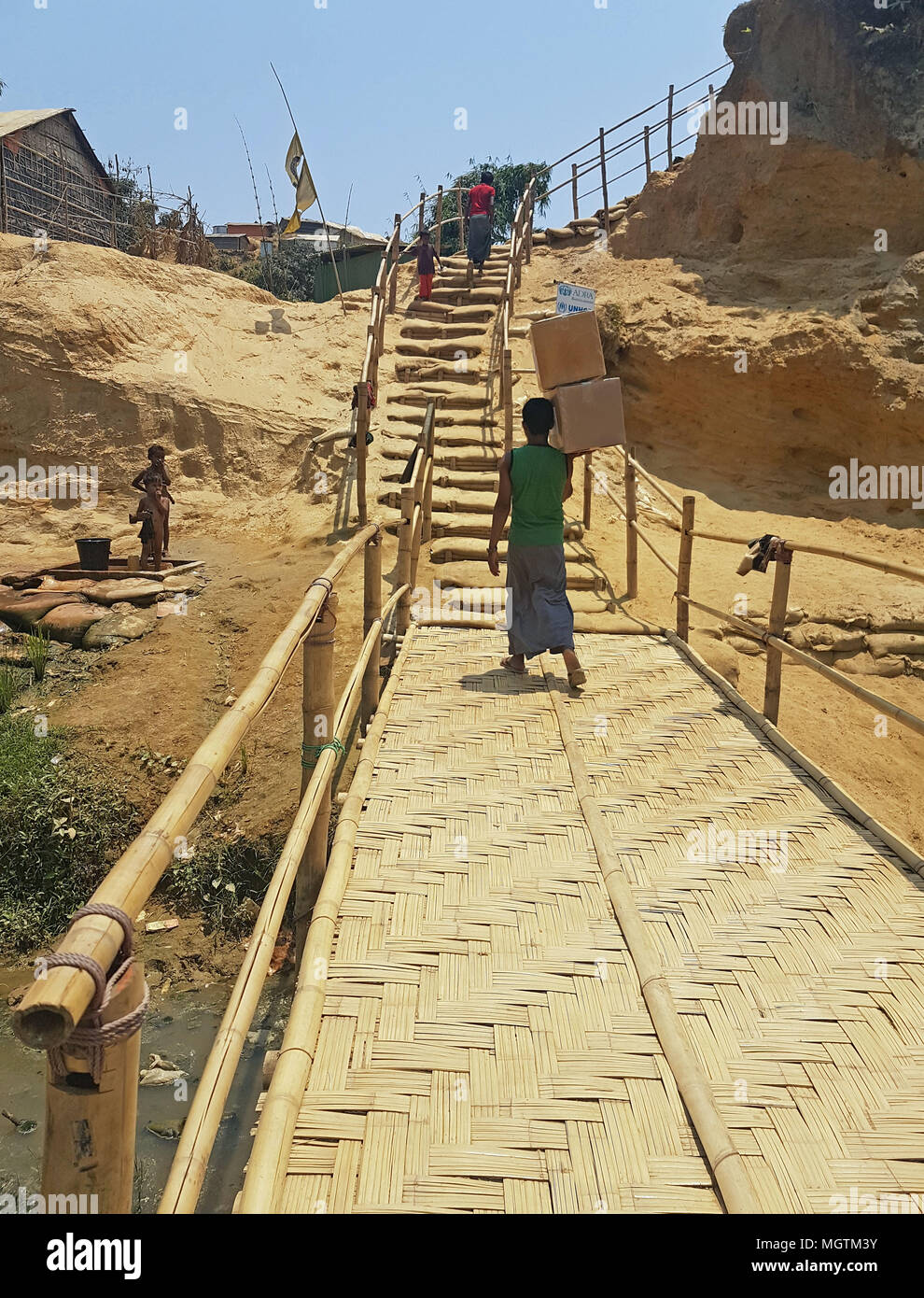 12 April 2018, Bangladesh, Cox·s Bazar: A Rohingya refugee walking across a bridge recently built by the UNHCR (United Nations High Commissioner for Refugees) in the Kerantoli camp. Aid organisations are working to prevent damages from the expected floodings and landslides during the upcoming monsoon season. Photo: Nick Kaiser/dpa - ATTENTION: only for use until the end of the public police search Stock Photo