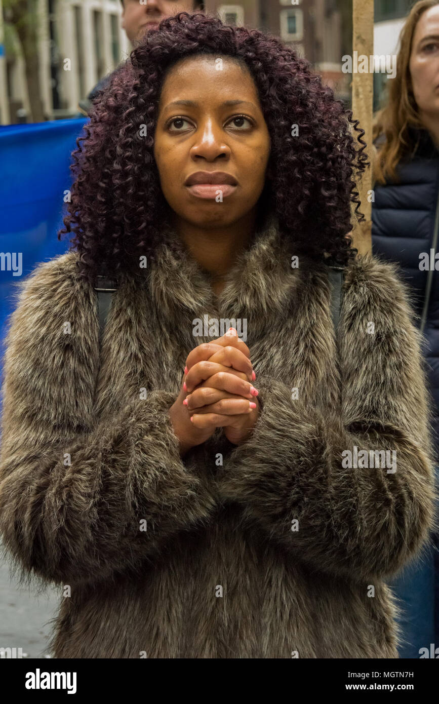 London, UK. 28 April 2018. A woman clasps her hands as she listens to speeches at the protest outside the Home Office. The protest was called by an individual disgusted by the government's incompetence and deliberately targeted attack on legal immigrants. Organiser Sara Burke wrote that ''the government's abhorrent treatment of those from the Windrush generation is a national embarrassment'' and planned the march to the Home office to put pressure on them to keep their promises to these people. Credit: ZUMA Press, Inc./Alamy Live News Stock Photo