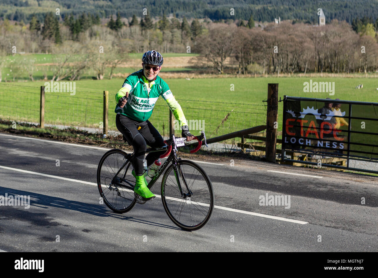 Fort Augustus, Scotland, UK. 29th April, 2018. Cyclists taking part in the Etape Loch Ness closed road cycle sportive following a 360-degree 66-mile / 106-Km route around Loch Ness, Scotland, starting and finishing in Inverness. This event is expected to attract 5,600 cyclists from across Scotland and the UK. Thousands of pounds will be raised by participants for Macmillan Cancer Support, the official event charity. This image shows a participant riding for Macmillan Cancer Support reaching the half way point near Fort Augustus. Cliff Green/Alamy Live News Stock Photo
