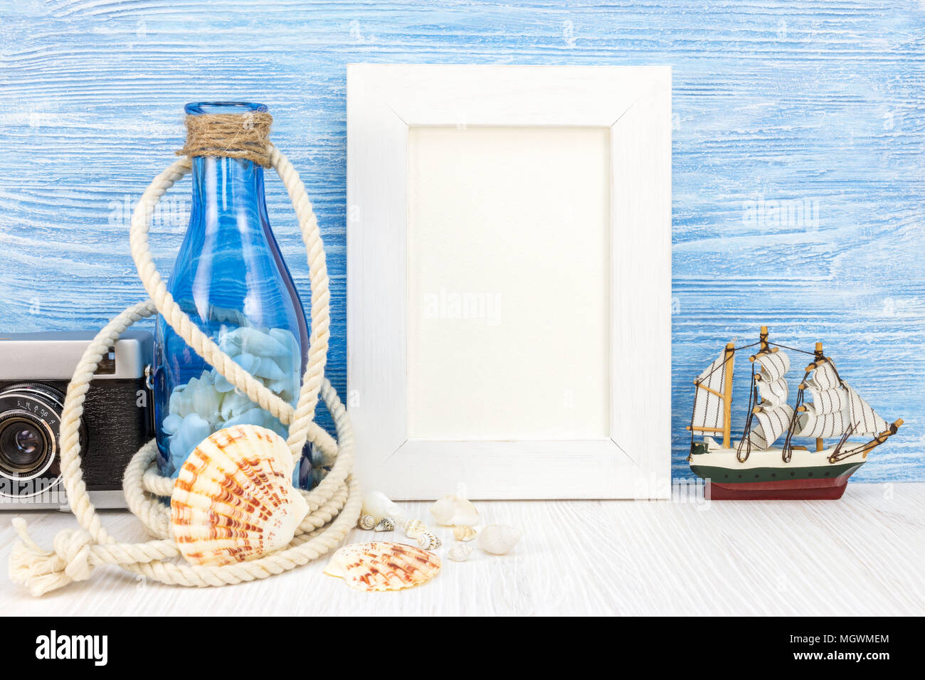 photo frame, retro camera, seashells and old bottle on blue boards background. summer vacation background Stock Photo
