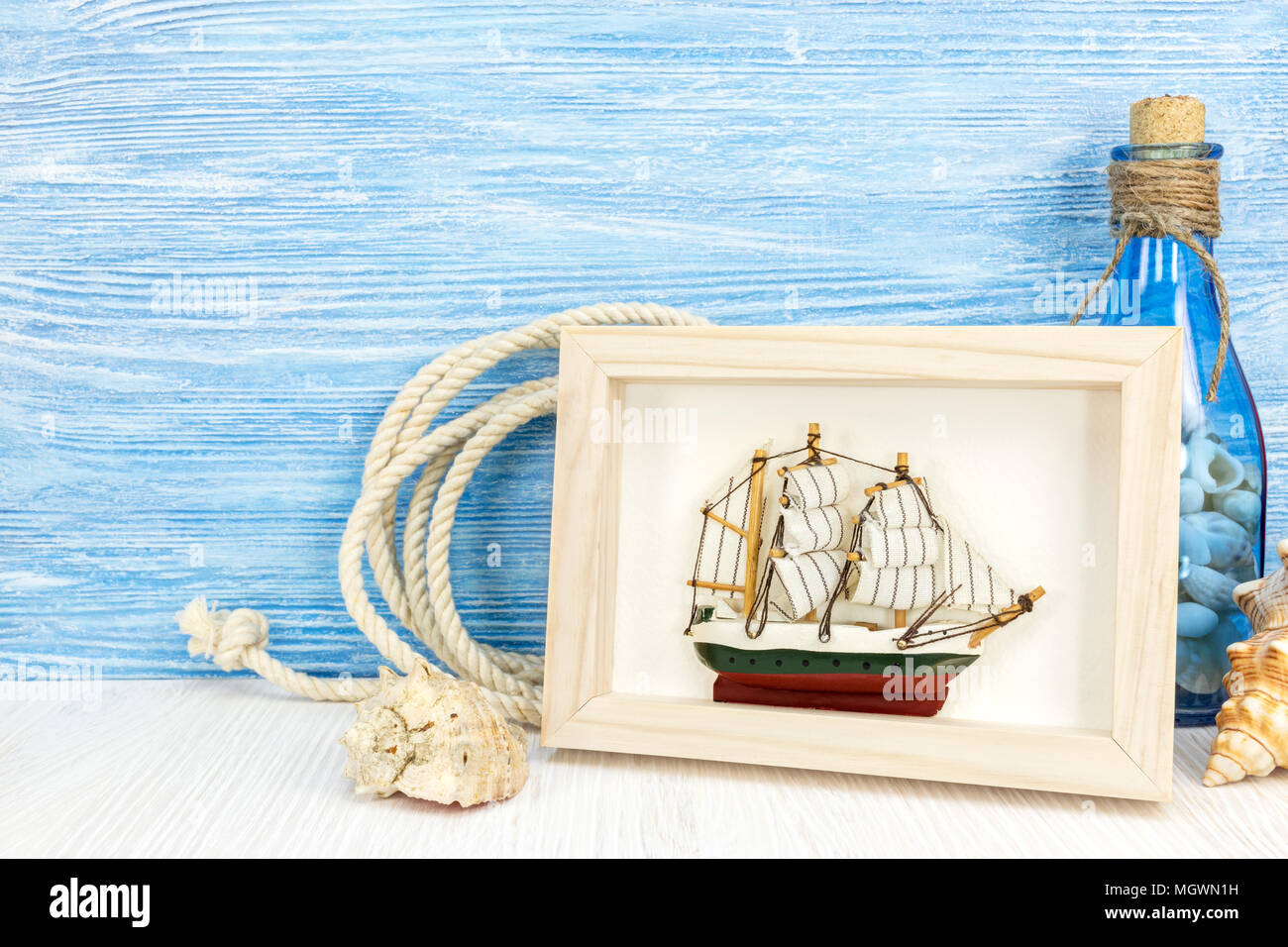 maritime background with sea shells, picture frame, ship and bottle on weathered blue wood  Stock Photo