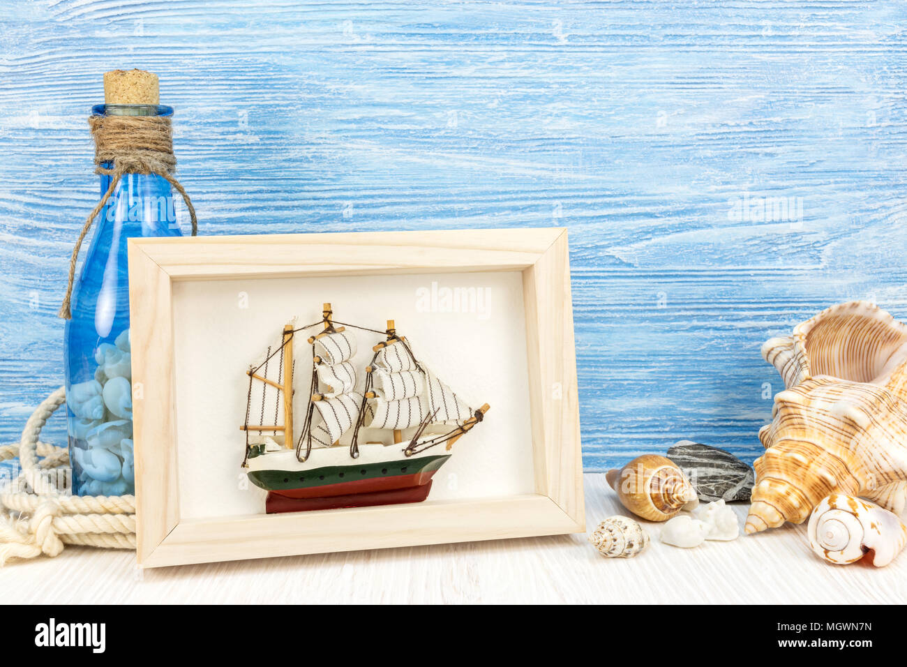 travel and vacation concept. seashells, photo frame, bottle and ship on blue wooden background Stock Photo