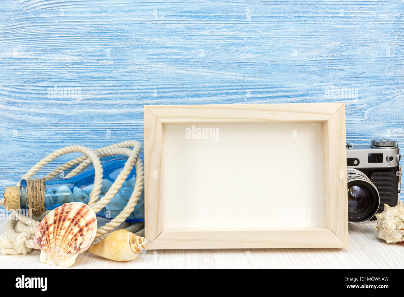 empty photo frame, seashells, bottle and classic camera on blue wooden background. vacation concept Stock Photo