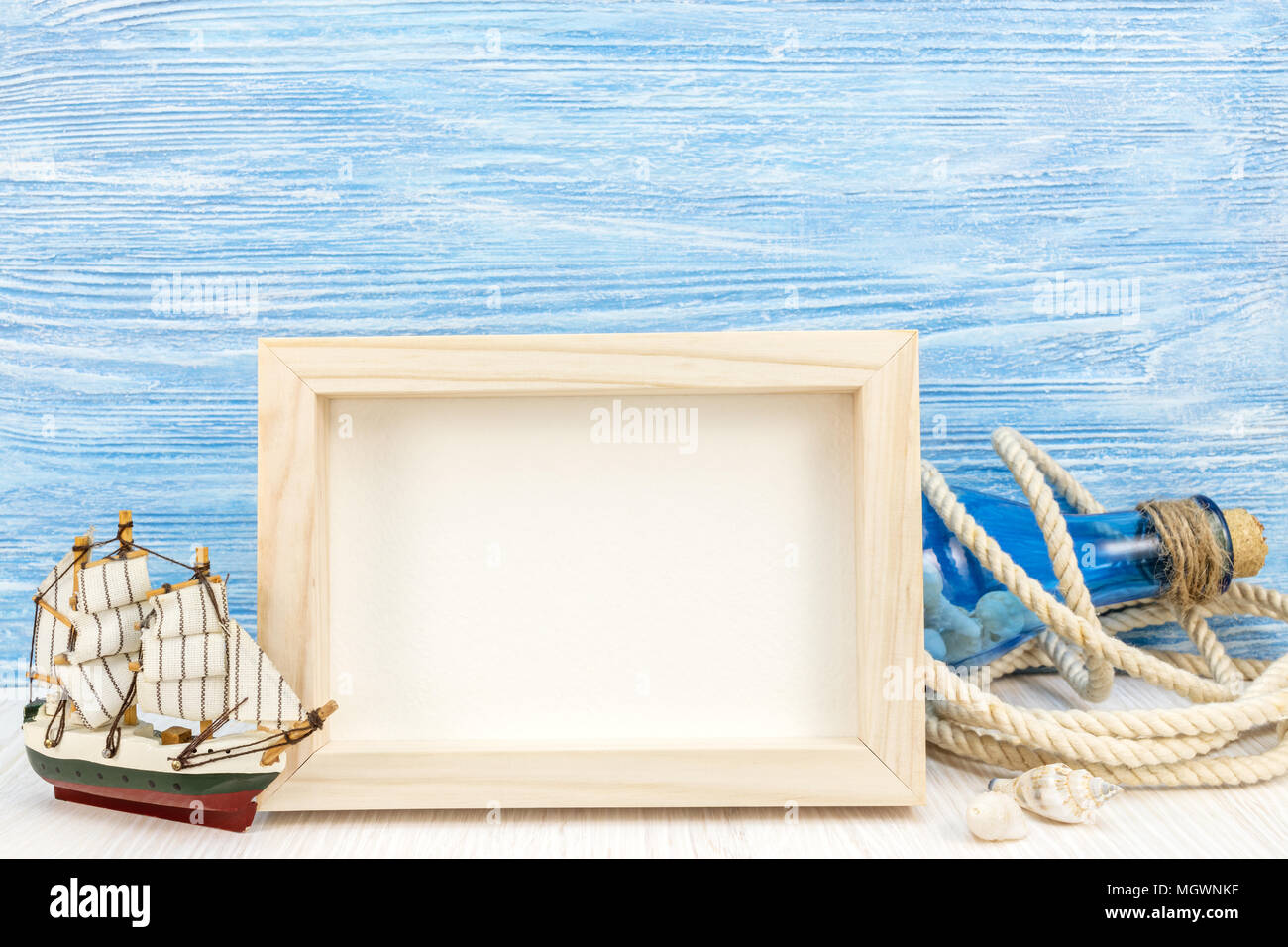 sea vacation background with photo frame, sailboat, rope and bottle against blue wooden boards Stock Photo