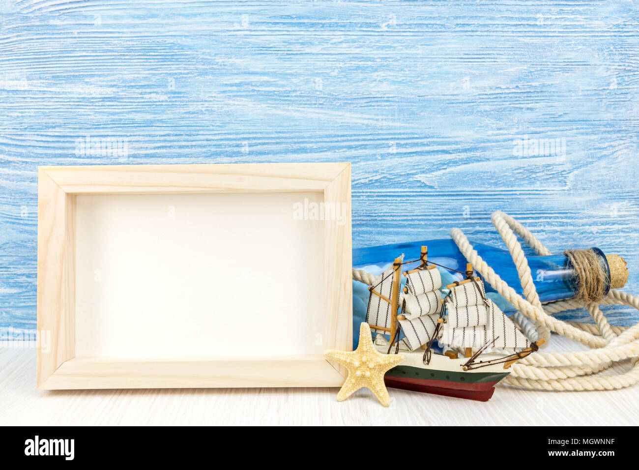 summer travel background with photo frame, blue glass bottle, seashells, rope, starfish and ship Stock Photo