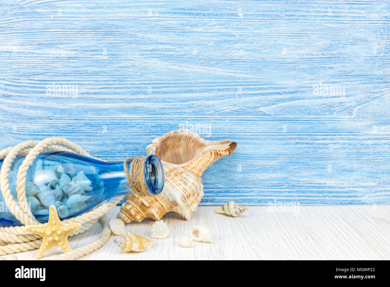 summer travel background with seashells, blue glass bottle and marine rope on weathered boards  Stock Photo
