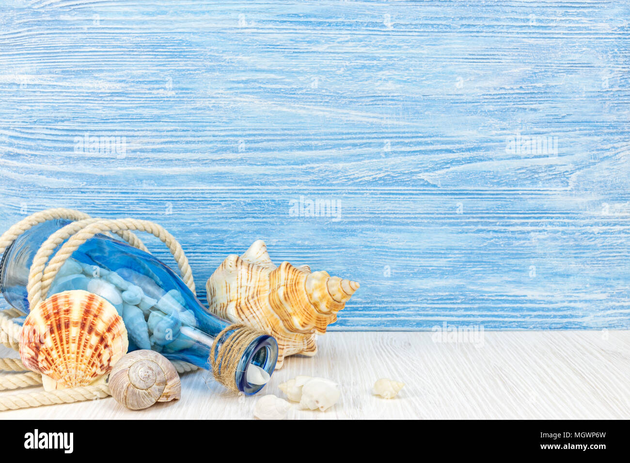 travel and vacation concept. blue glass bottle with seashells and rope on wooden background  Stock Photo