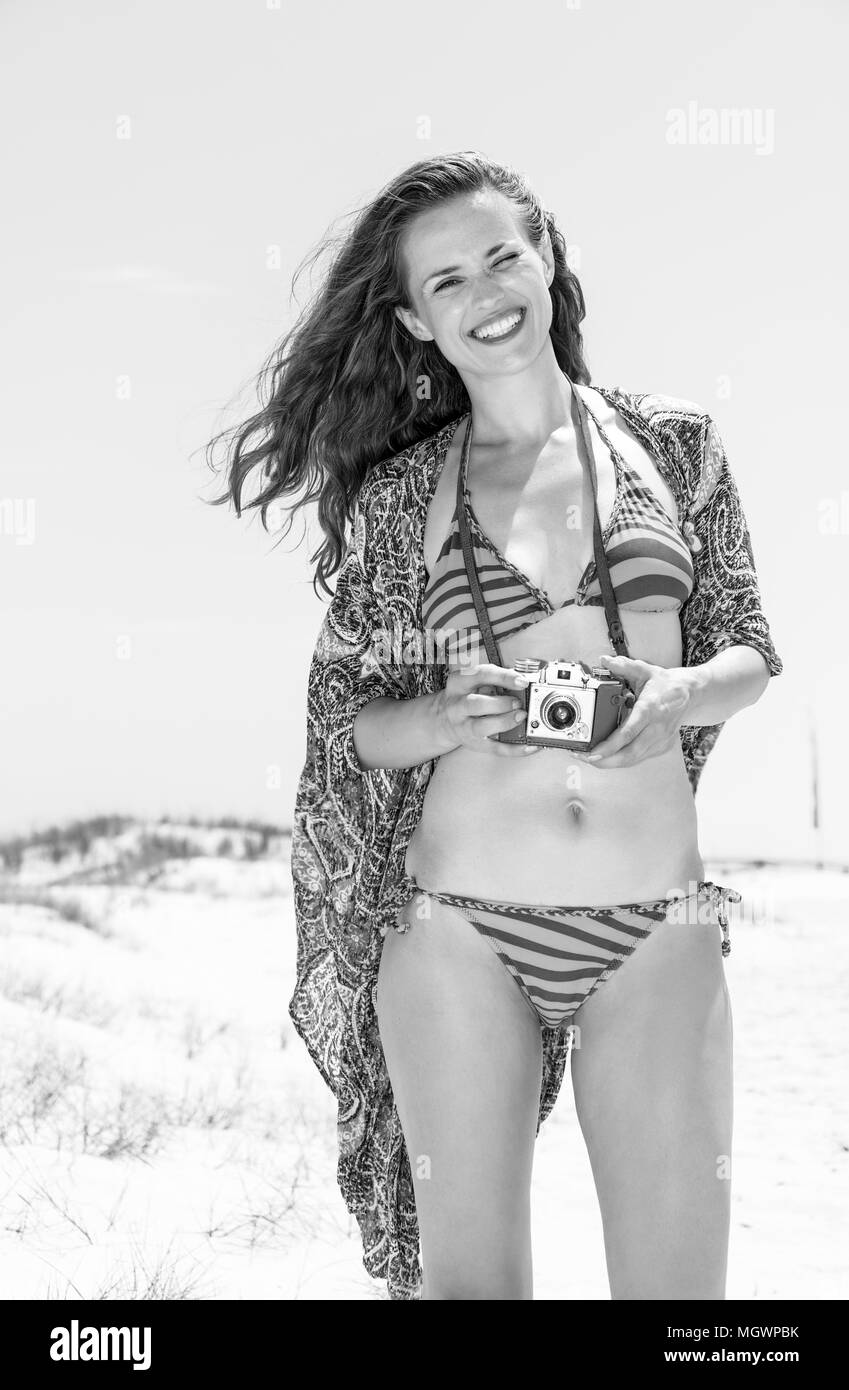 Bohemian vibe vacation. Portrait of happy hipster young woman in bikini on the beach with retro photo camera Stock Photo