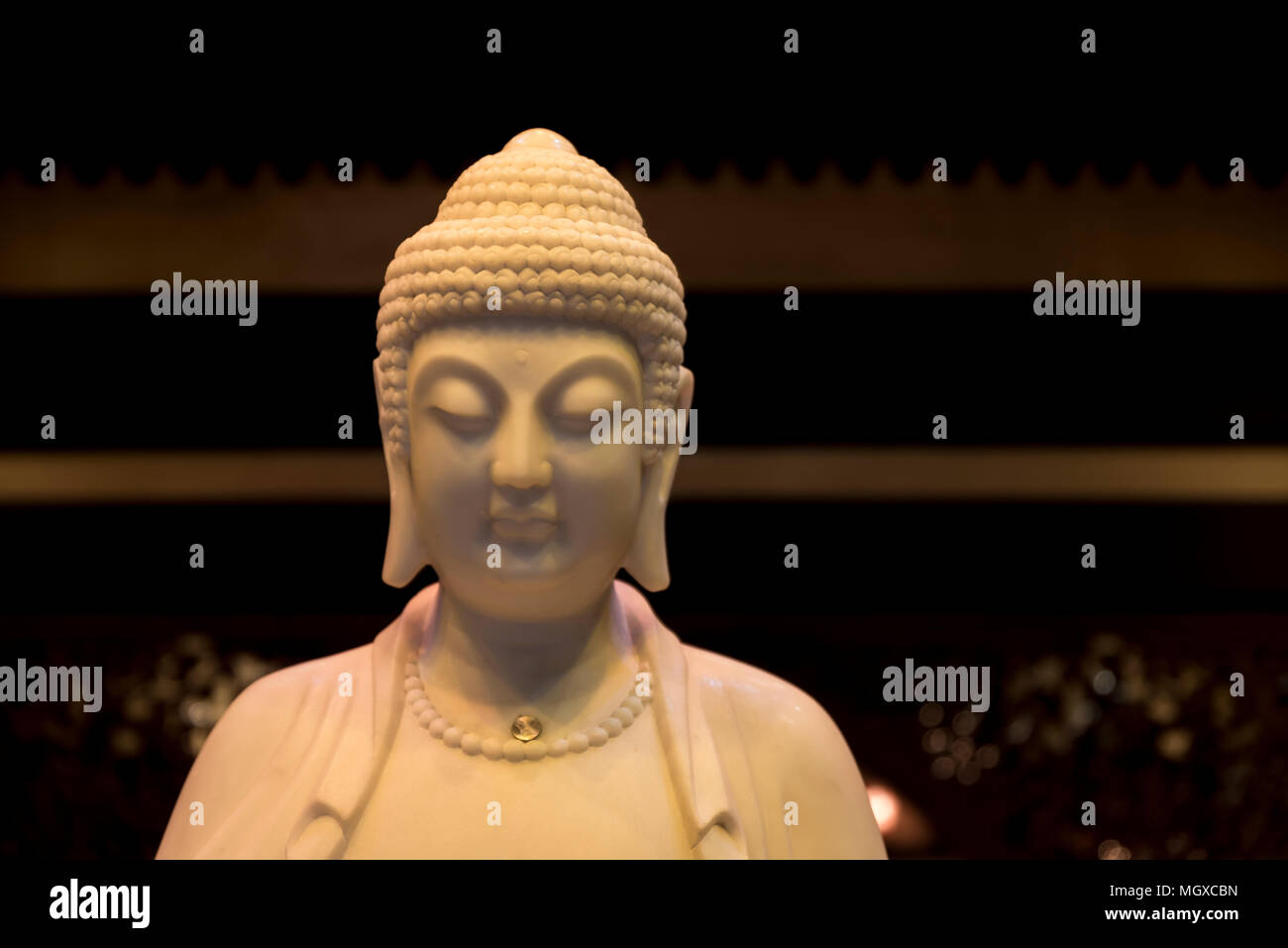 Head and shoulders of the Buddha, in mock ivory material Stock Photo