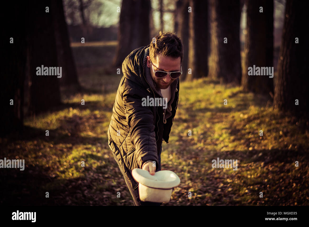 Portrait of a young men, gentleman, with a beard, hat and sunglasses, bowing; outdoor, nature Stock Photo