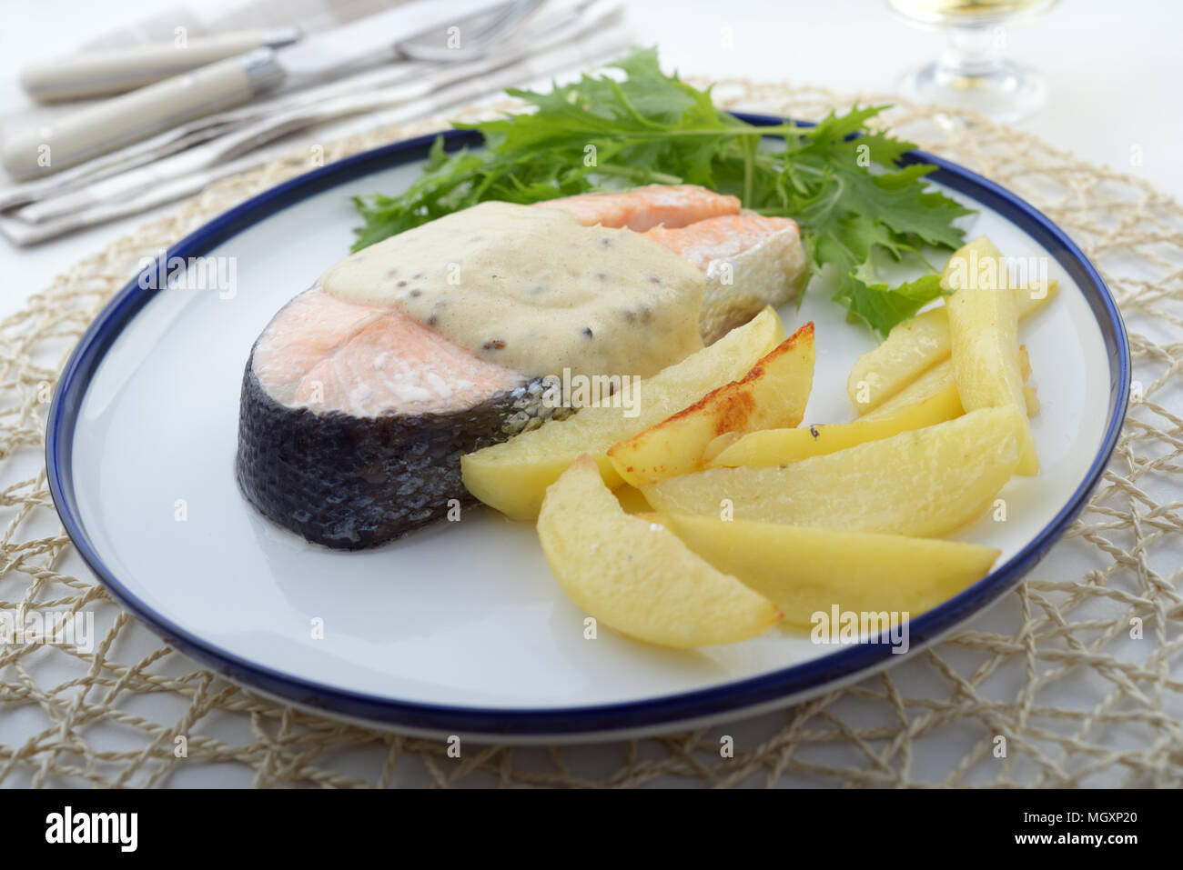 Baked salmon with potato, mustard sauce, and mizuna Stock Photo
