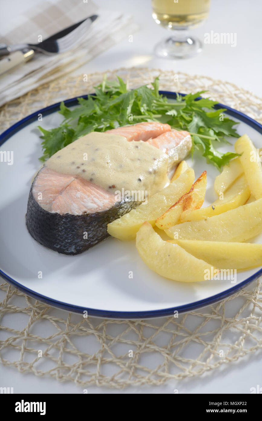 Baked salmon with potato, mustard sauce, and mizuna Stock Photo