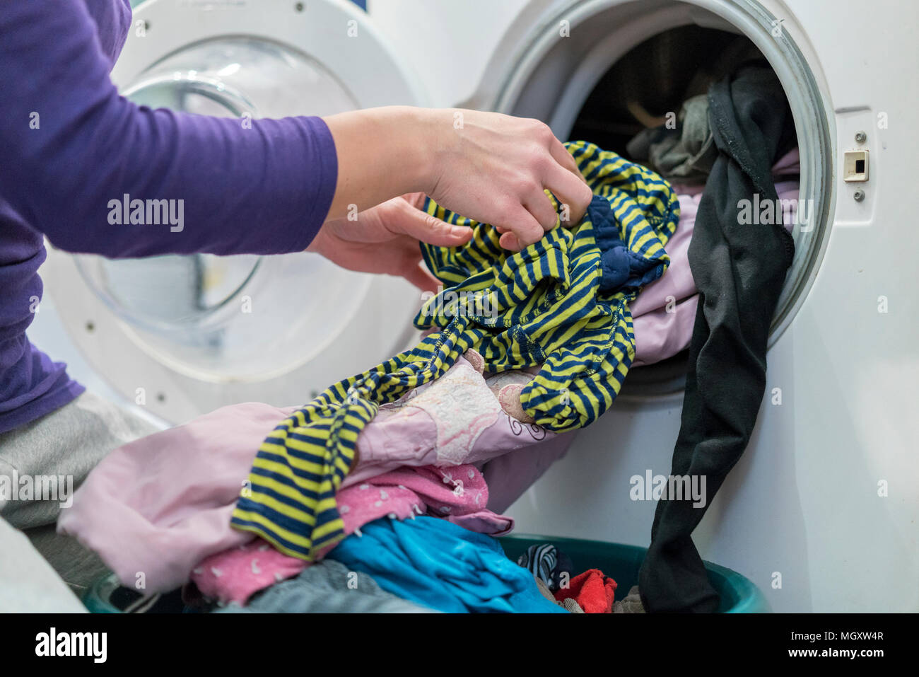 Preparing the wash cycle. Washing machine, hands and clothes Stock