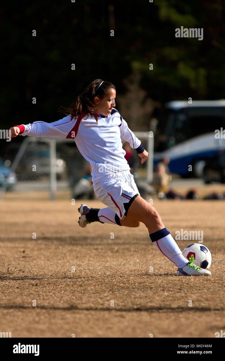 Female high school soccer player strikes ball in tournament game Stock