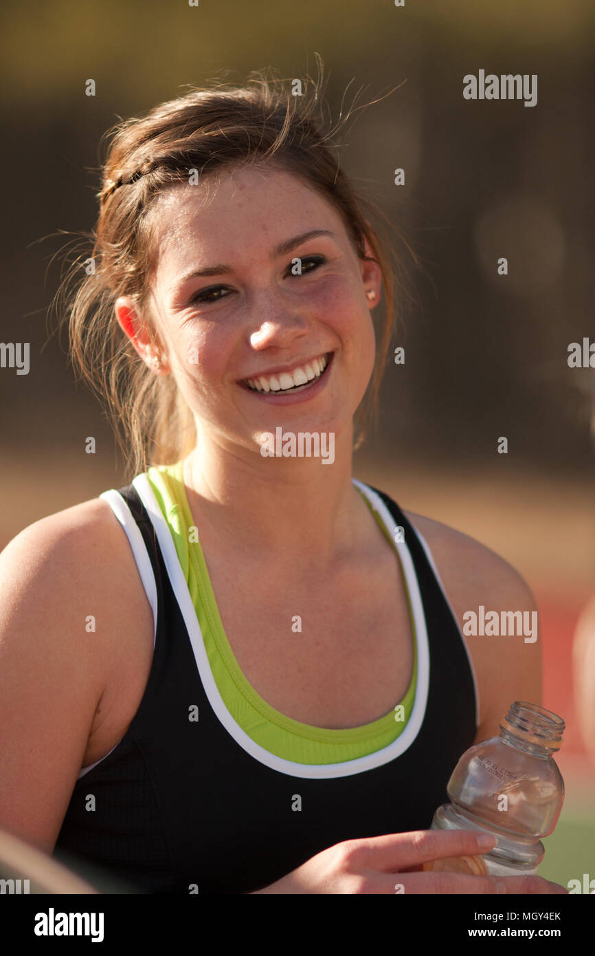 Female high school tennis player smiles during match Stock Photo