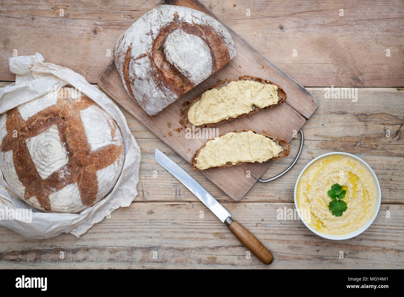 Sourdough bread and spelt sourdough bread with homemade hummus on a bread board. UK. Stock Photo