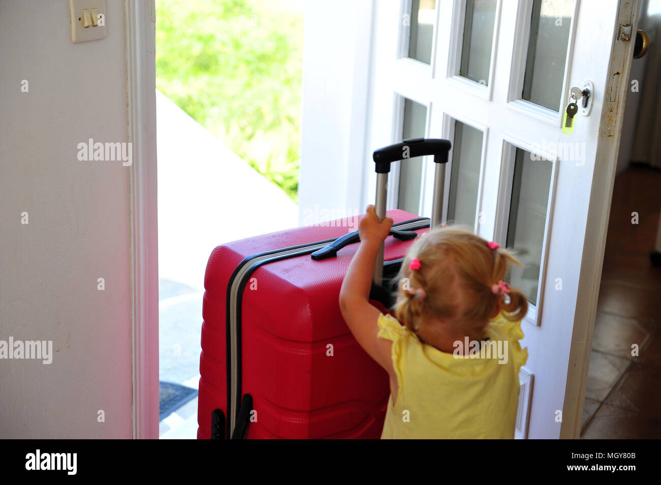 Baby girl with suitcase at the door Stock Photo Alamy