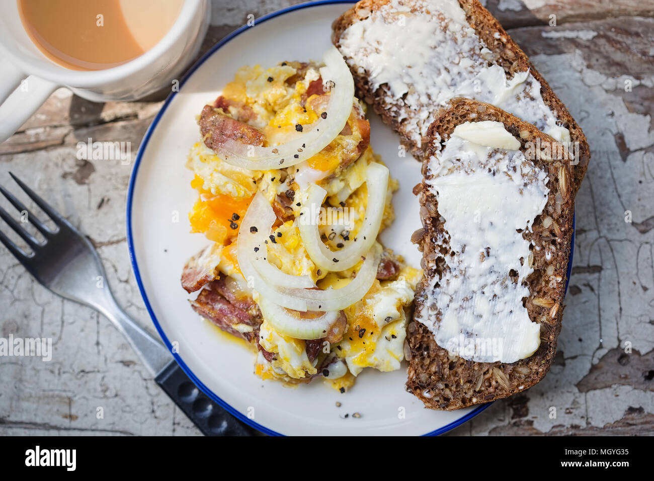 Scrambled eggs with bacon, sausage and onion with wholegrain bread and